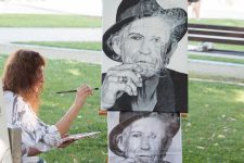 Woman artist painting a portrait in Zvolen park on a sunny day.