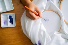 A detailed view of hand-painted floral design on fabric using watercolor brushes.